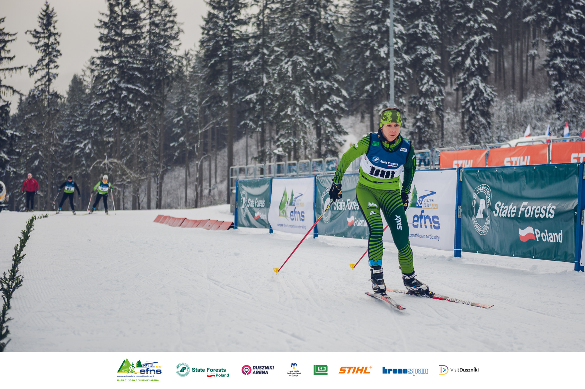 Athletin bei der Nordischen Ski EM der Förster (EFNS) fährt Rennen, im Hintergrund STIHL Banner