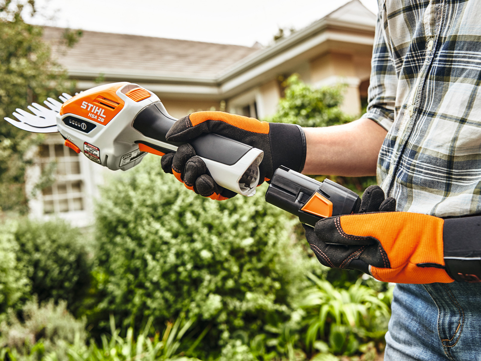 Frau beim Einstecken des Akkus STIHL AS 2 in die Akku-Strauchschere STIHL HSA 26.