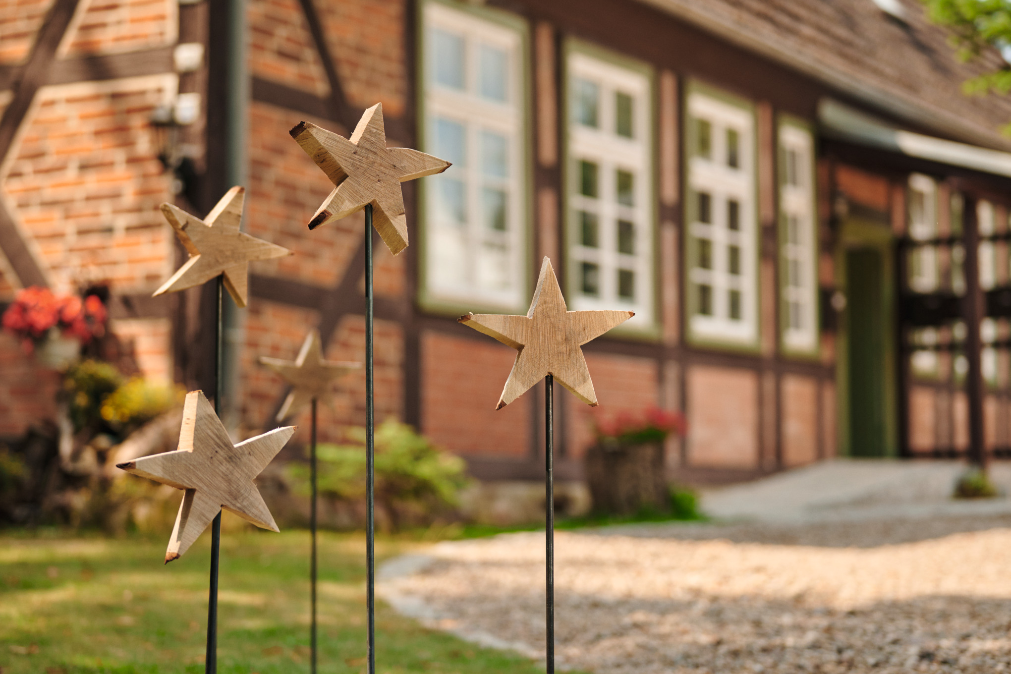 Sterne aus Holz am Stab vor einem Haus
