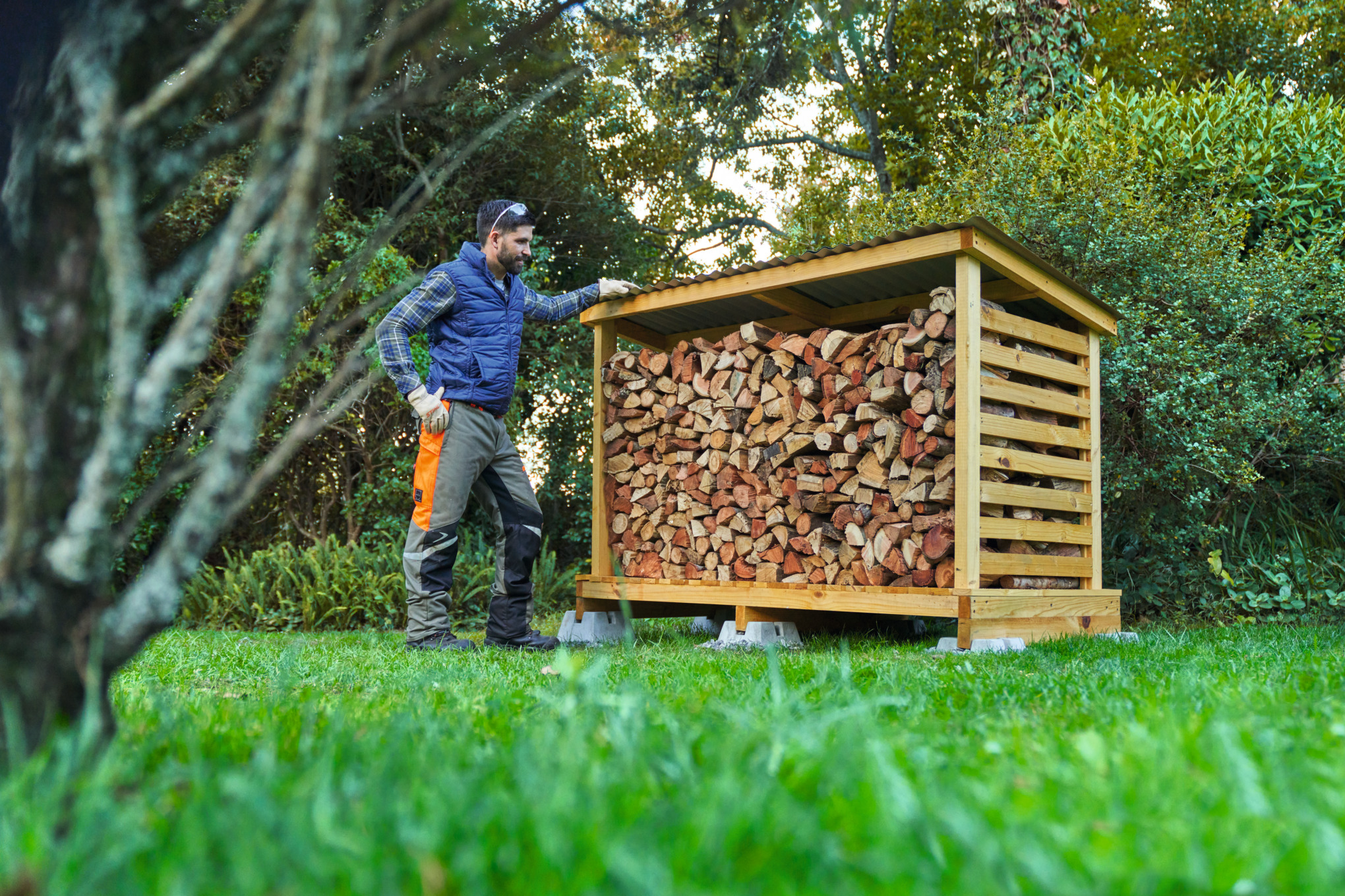 Mann in Schutzausrüstung vor einem selbstgebauten Holzunterstand