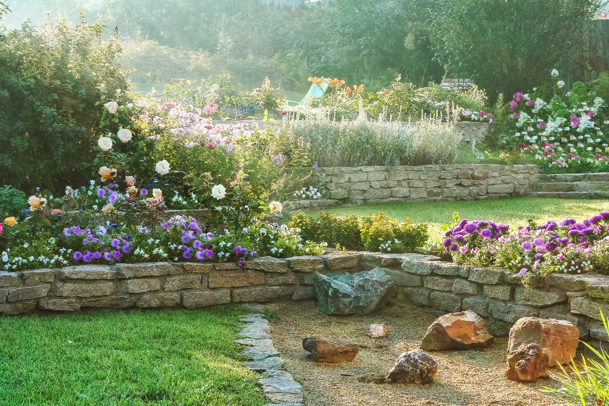 Hanggarten mit Steinmauern, bunten Blumen und Rasenflächen