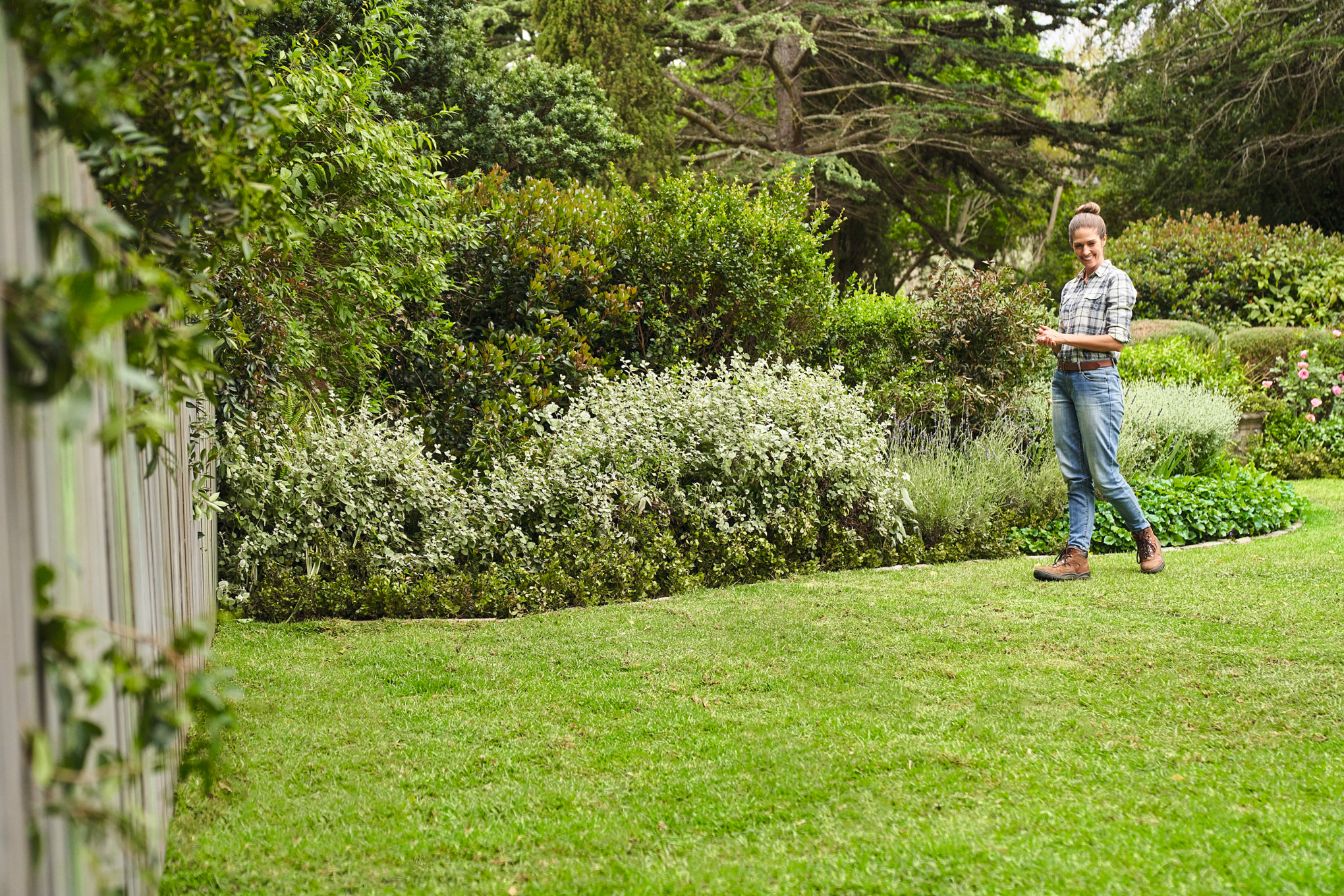 Frau begeht Ihren neu verlegten Rollrasen in einem großen Garten 