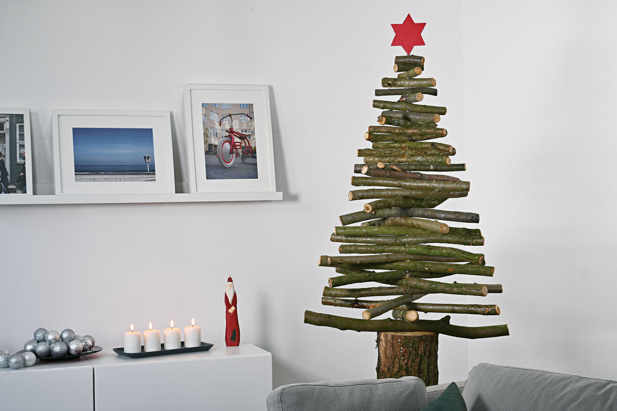 Selbstgebauter Weihnachtsbaum aus Holzzweigen mit rotem Stern auf der Spitze in einem weihnachtlich geschmückten Innenraum