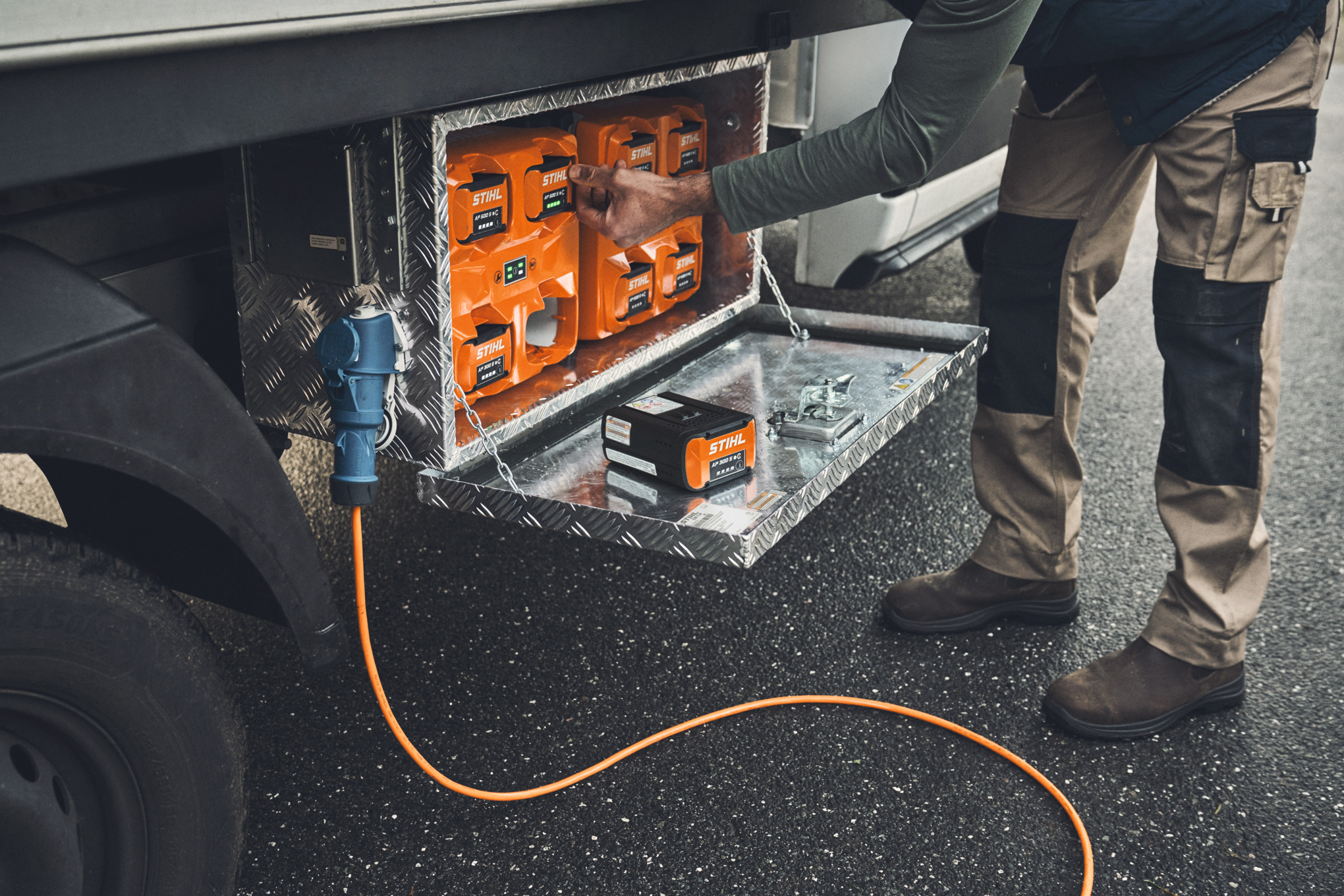 Ein Mann holt einen aufgeladenen STIHL Akku AP 500 aus der Ladebox