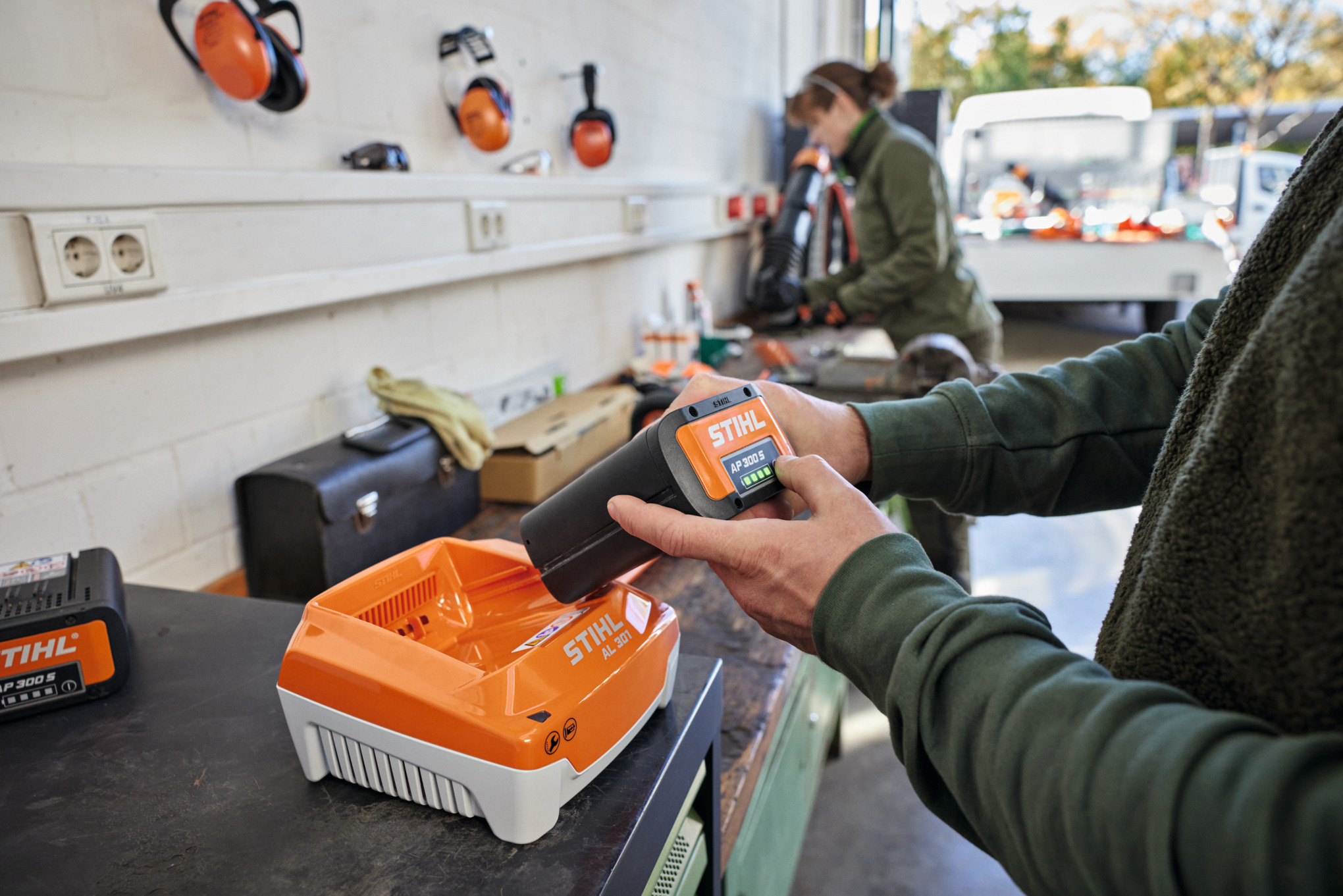 Eine Person steckt einen Akku STIHL AP 300 S in ein Schnellladegerät STIHL AL 301