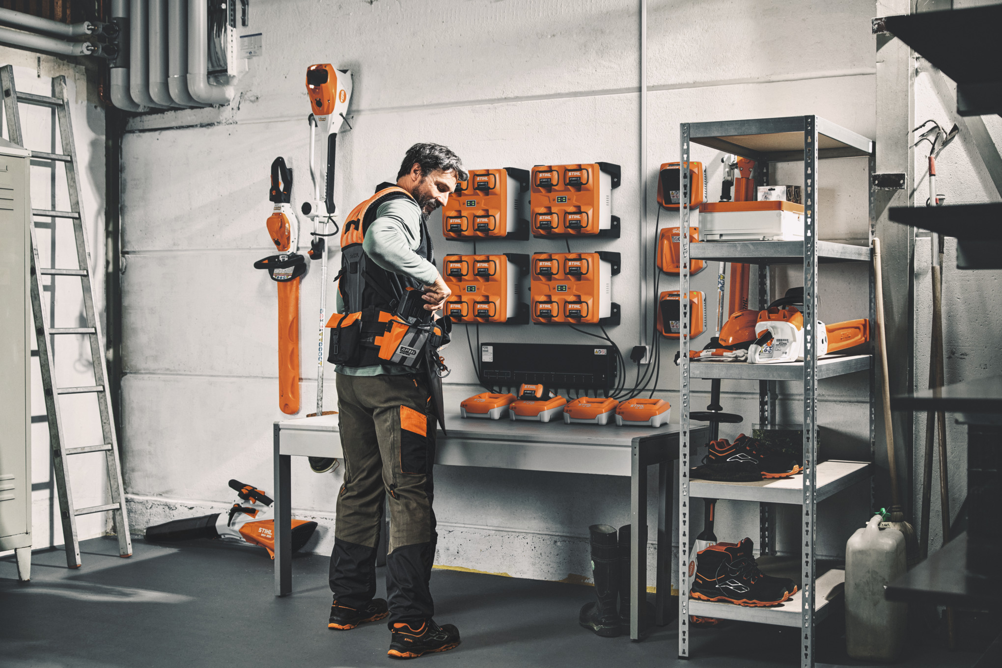 Mann in einer Werkstatt bereitet sein modulares Gürtelsystem ADVANCE X-Flex mit geladenen Batterien aus dem Lademanagement CM 12 vor.
