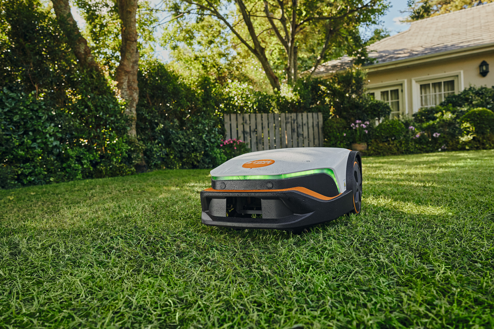 Roter Mohn, Kornblumen und weitere Wildblumen, im Hintergrund ein STIHL iMOW® Mähroboter mit Ladestation in einem Garten