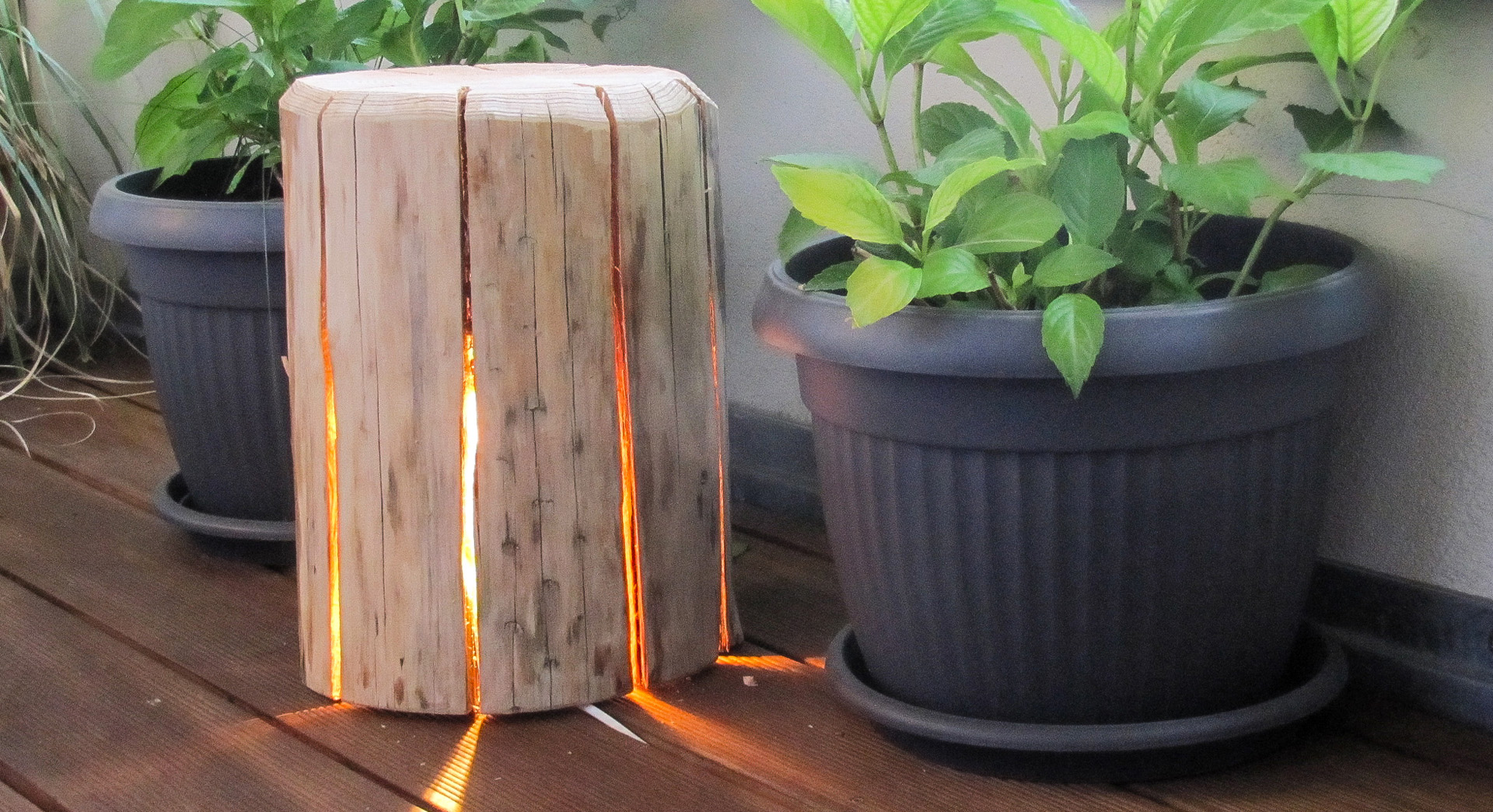 Lampe aus Holz zum Selberbauen steht zwischen zwei Pflanzentöpfen, im Inneren leuchtet eine Lichterkette