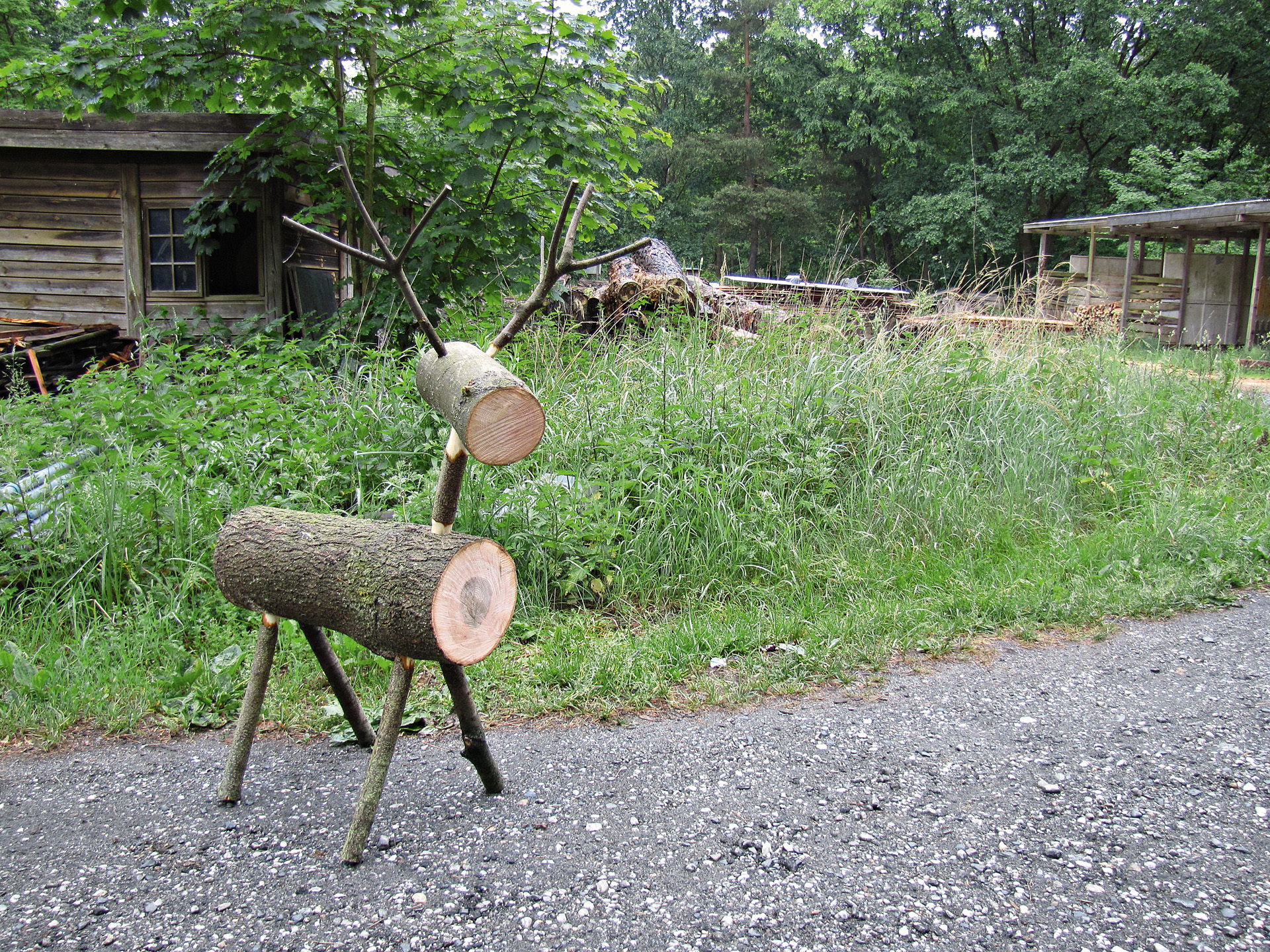 Rentier aus Holz vor grünem Rasen und Holzhütte