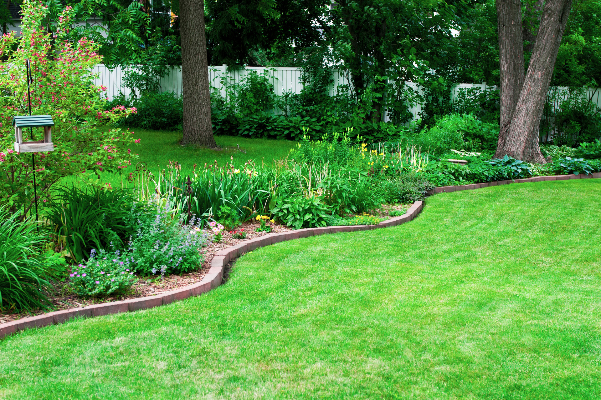 Gartenbeet mit einer selber gemachten Beeteinfassung aus Steinen an grünem Rasen