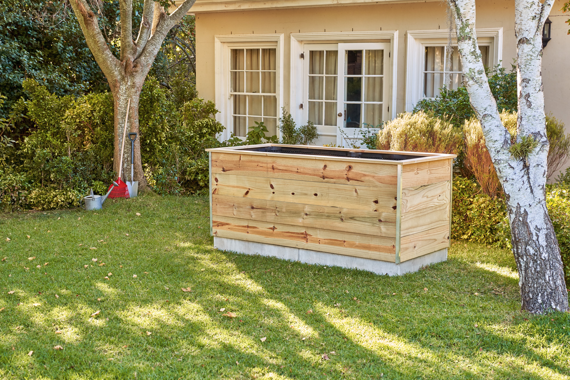 Hochbeet aus Holz zum Selberbauen steht im Garten vor einem Haus