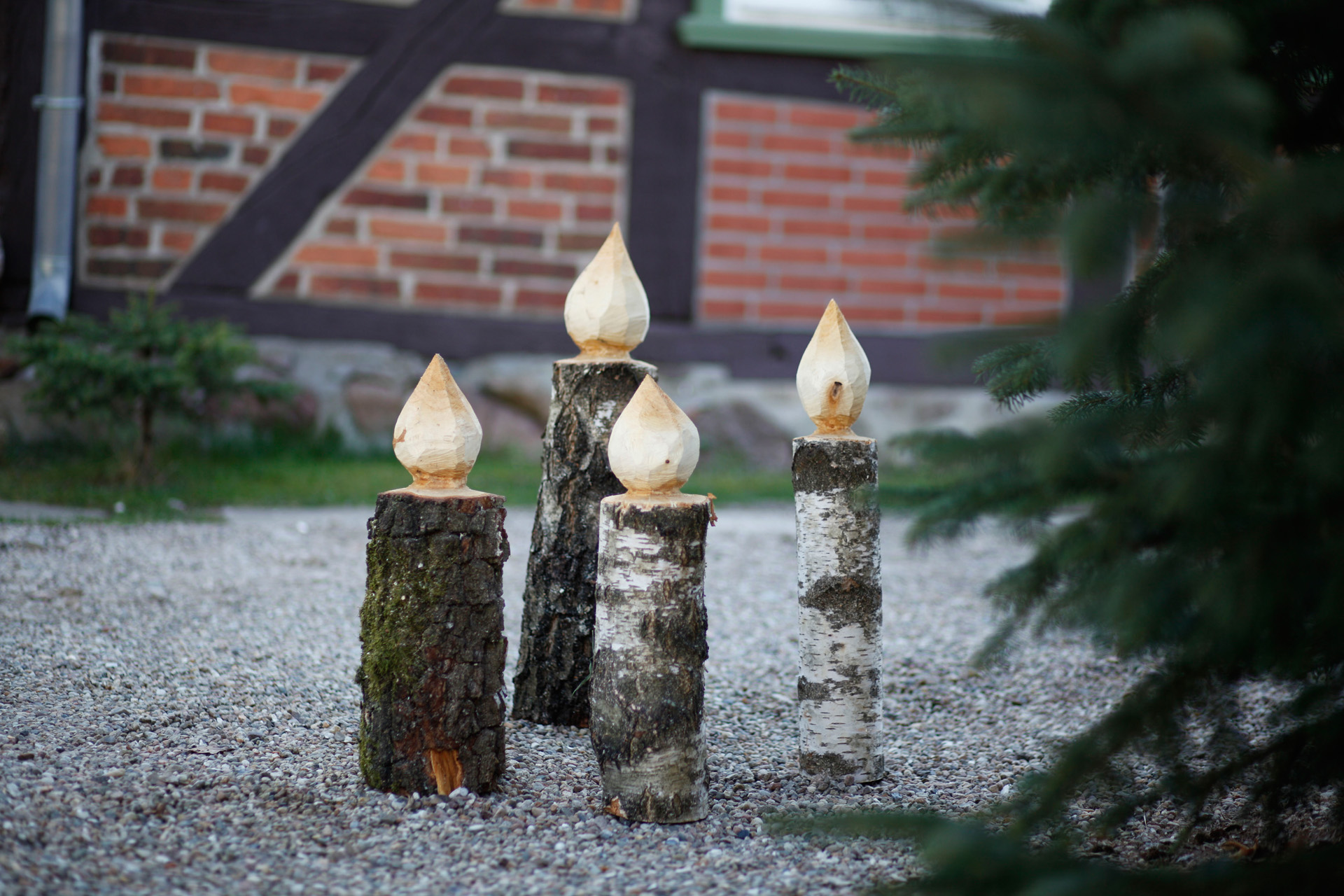 Vier Kerzen aus Holz zum Selbermachen neben einem Tannenbaum