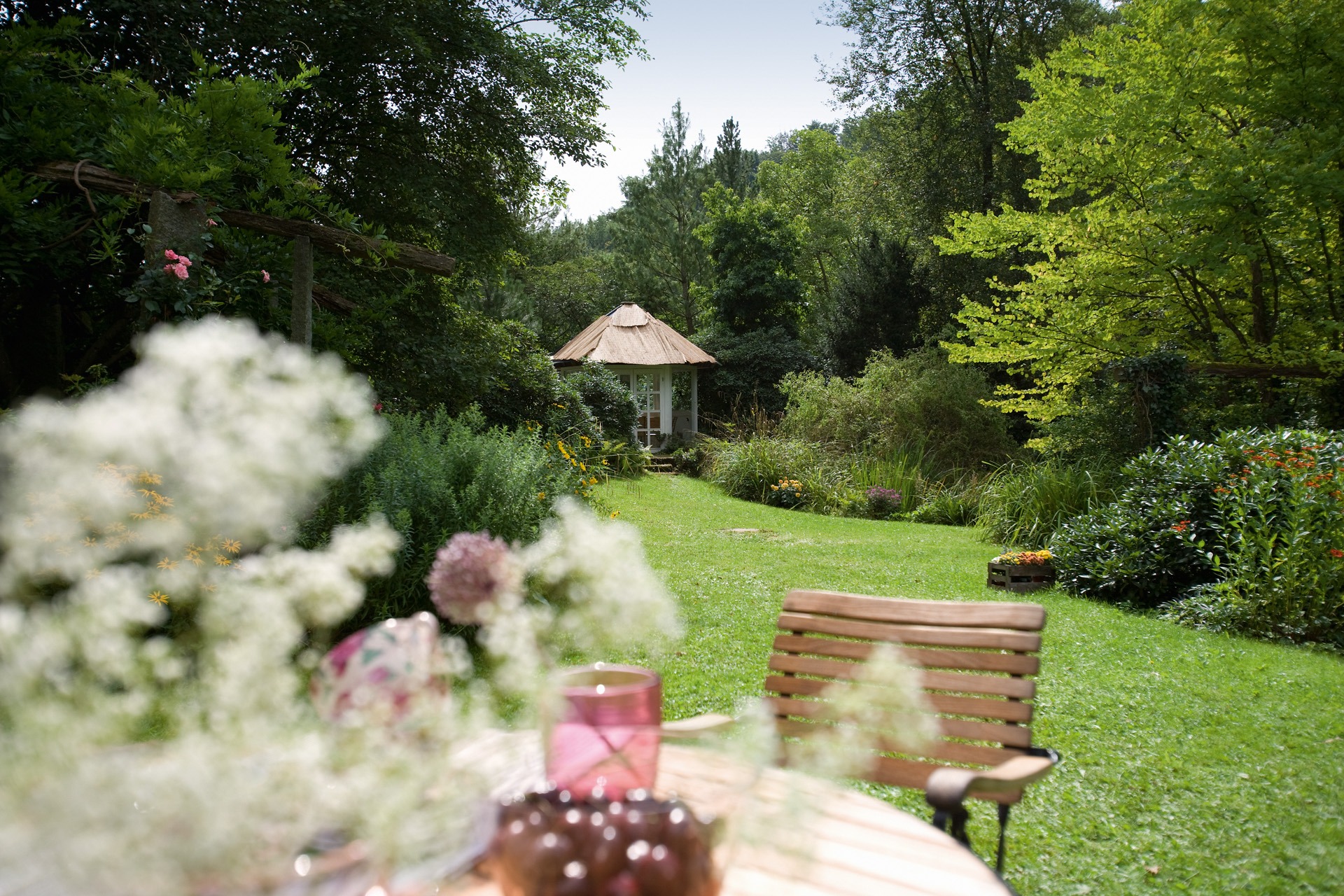 Gartenpflege in grünem Garten mit Stuhl im Vordergrund und Schuppen im Hintergrund