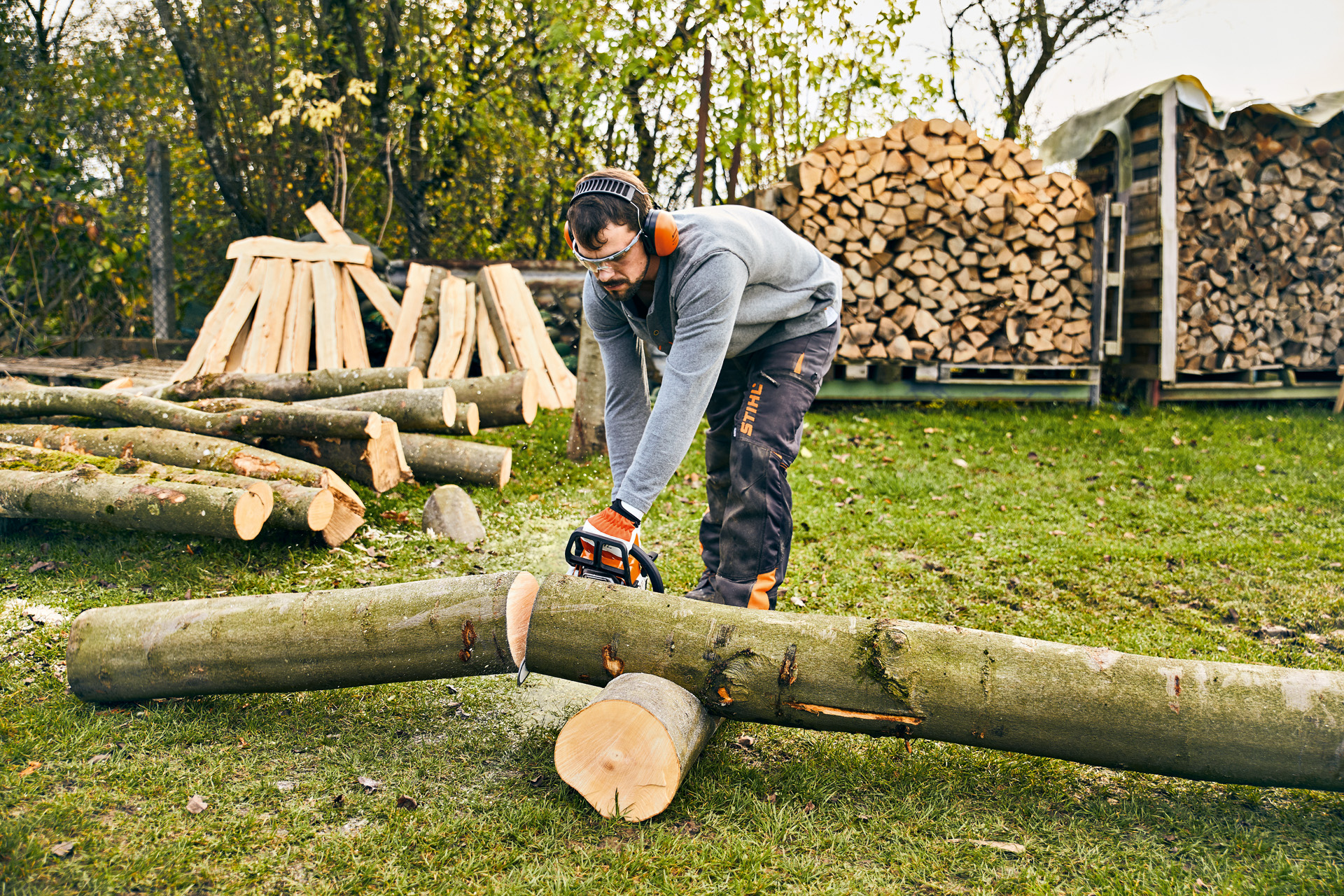 Mann möchte Pflanztrog selber bauen und zersägt dazu einen Baumstamm mit der STIHL Benzin-Motorsäge MS 180.