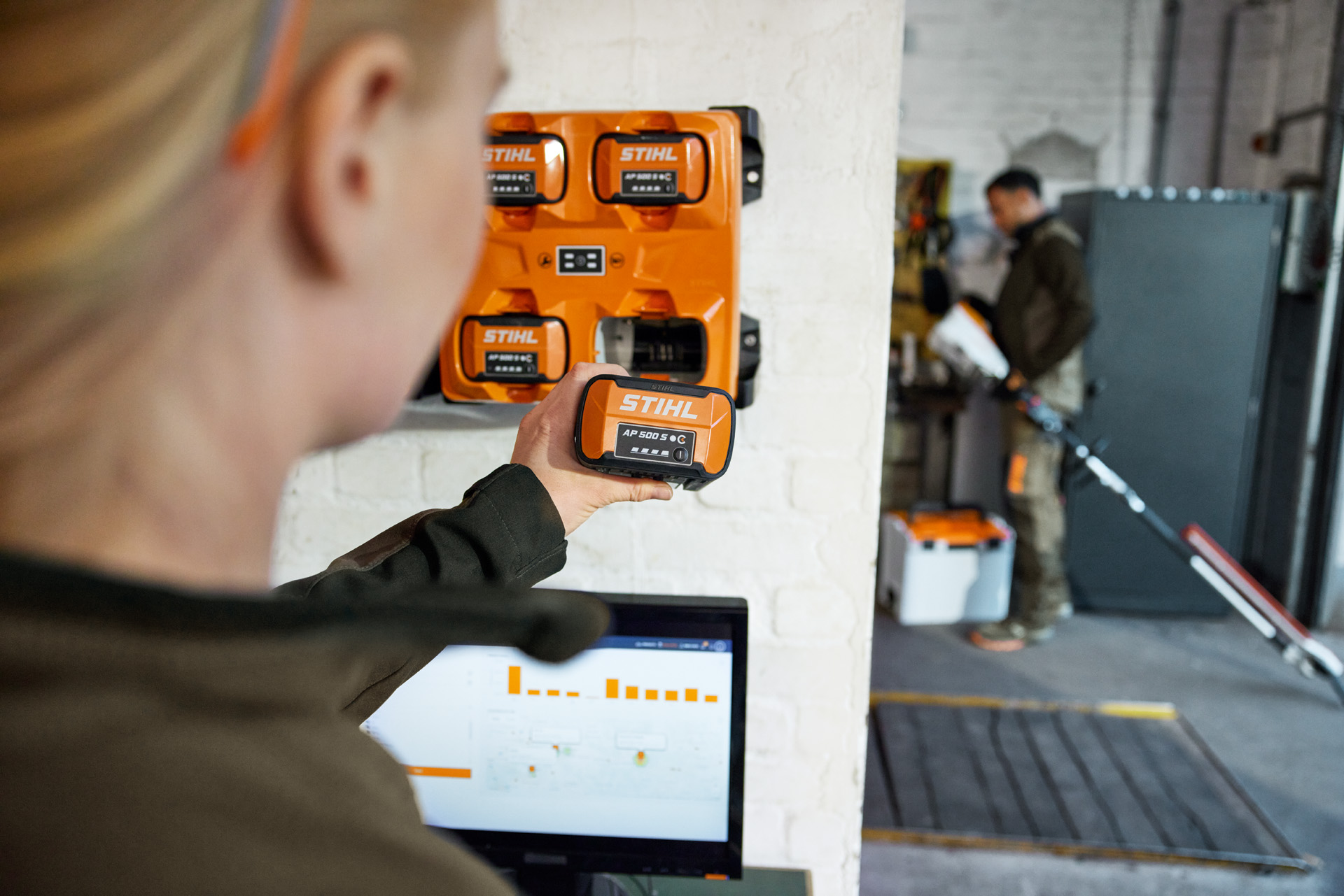 Frau in einer Garage vor einem Laptop mit dem STIHL Akku AP 500 S