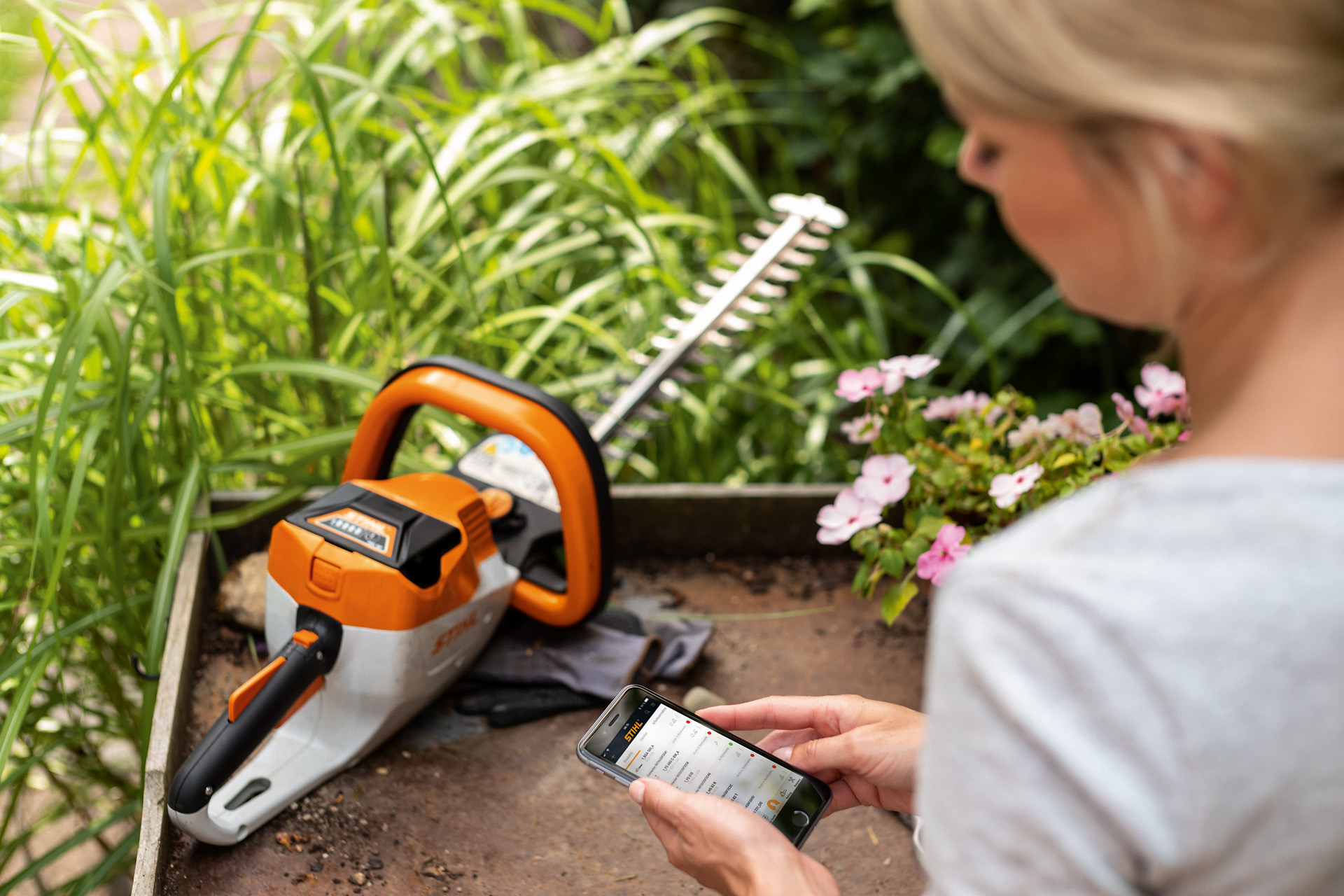 Frau registriert ihre STIHL Heckenschere mit der STIHL App auf einem Smart Phone