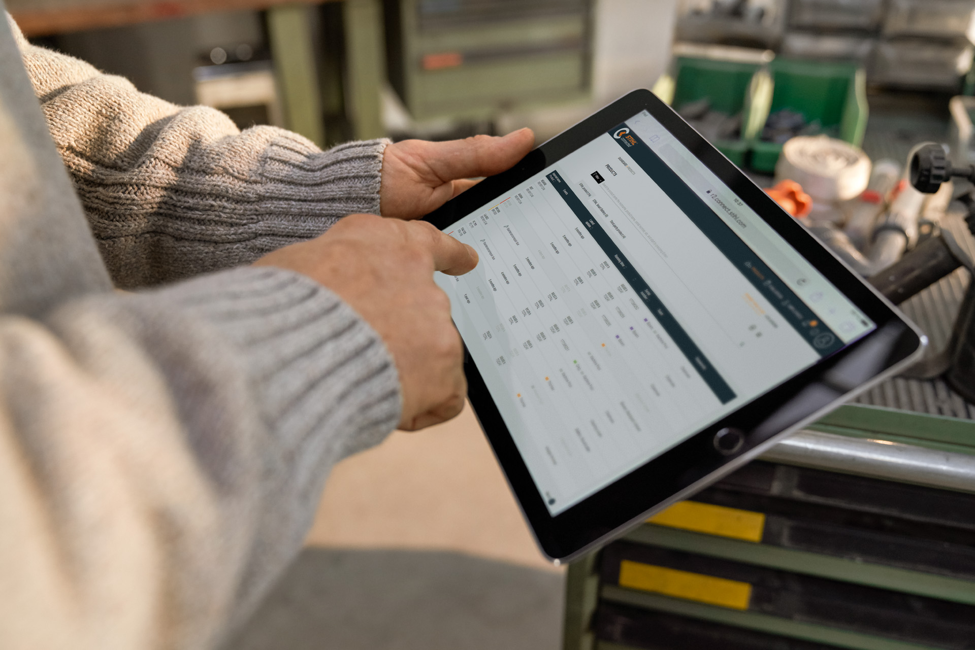 Person bedient ein Tablet, das Display zeigt das STIHL connected Portal