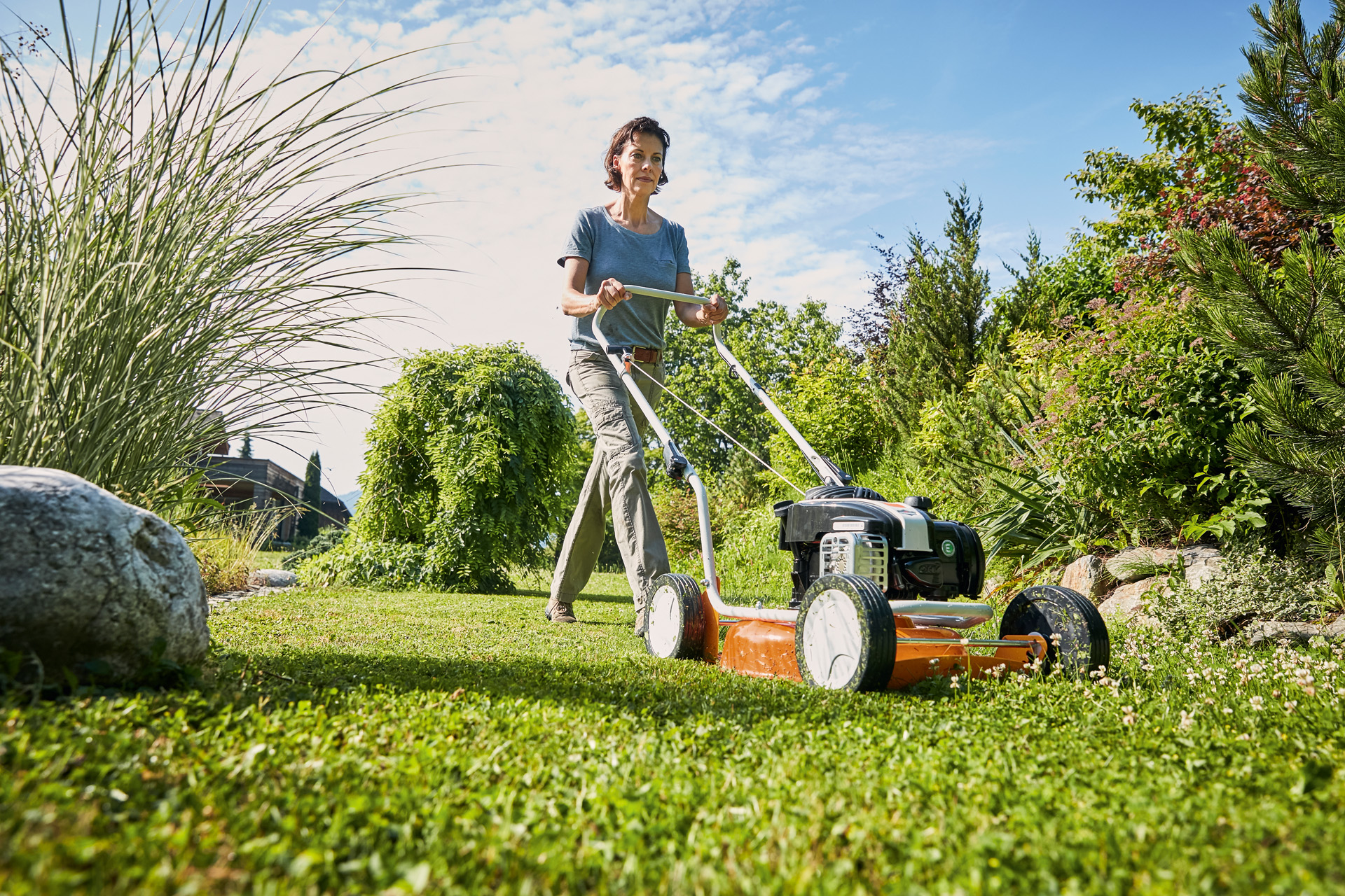 Frau beim Mulchen mit einem STIHL Benzin-Mulchmäher RM 2 R auf einem grünen Grundstück