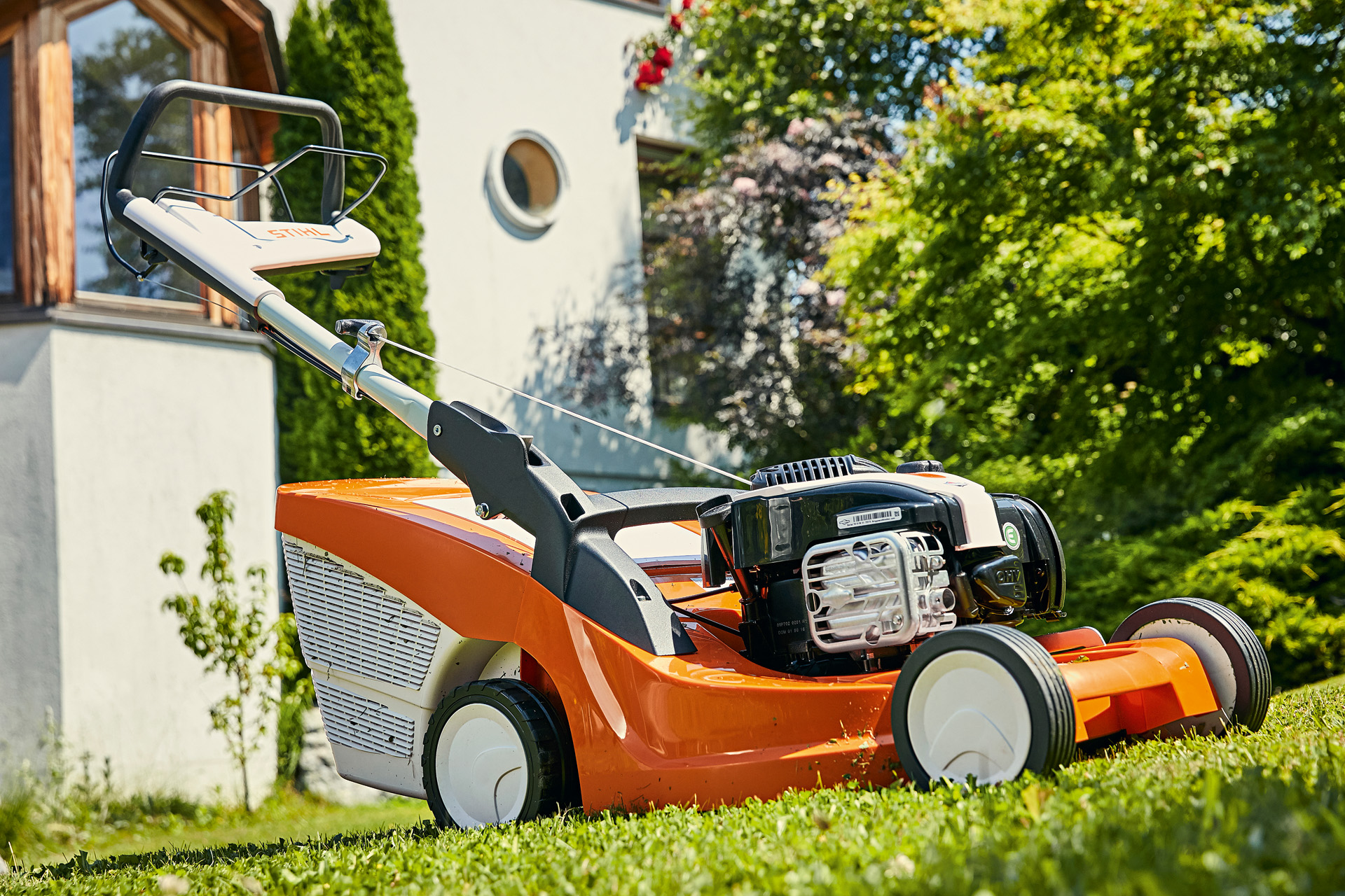 STIHL Benzin-Rasenmäher RM 443 T auf grünem Rasen vor einem Haus