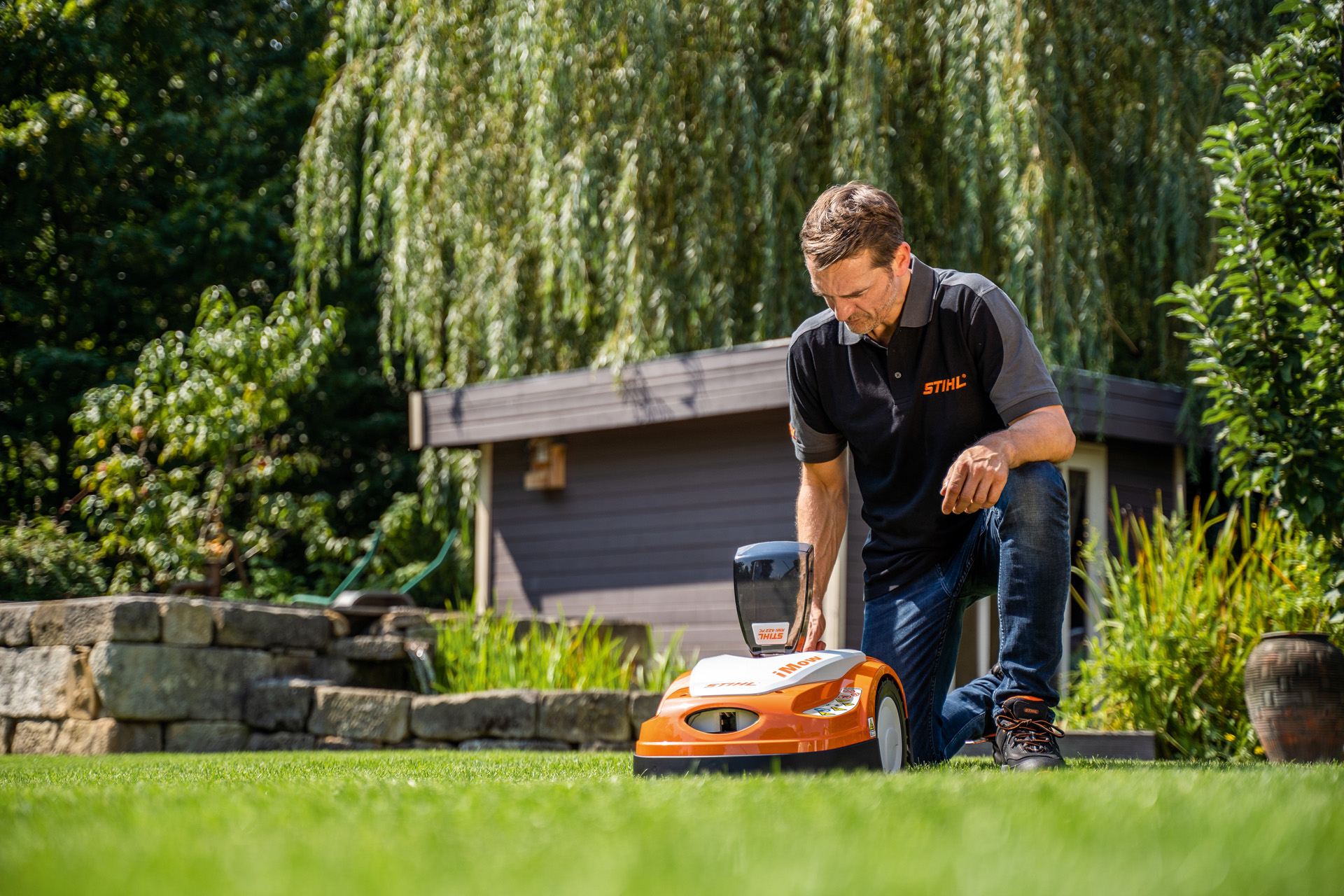 STIHL Fachhändler programmiert den Mähplan eines STIHL iMOW Mähroboters in einem Garten