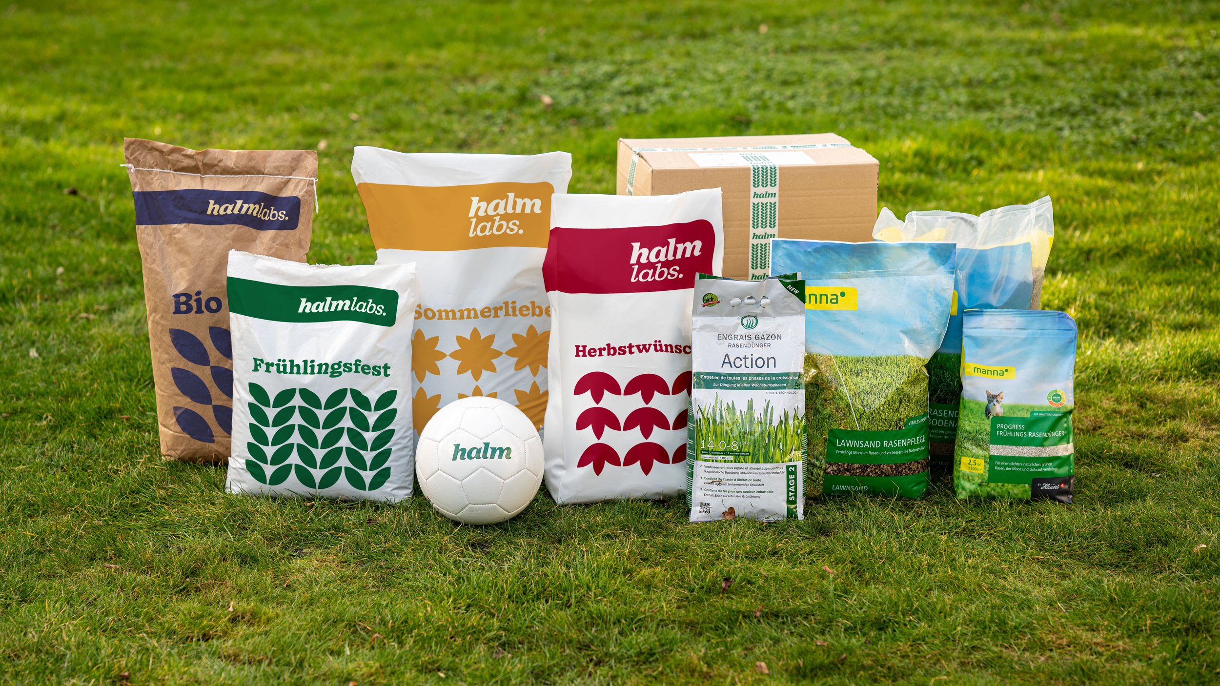 Halm-Produkte für die Rasenpflege nebeneinander angeordnet auf einer Rasenfläche