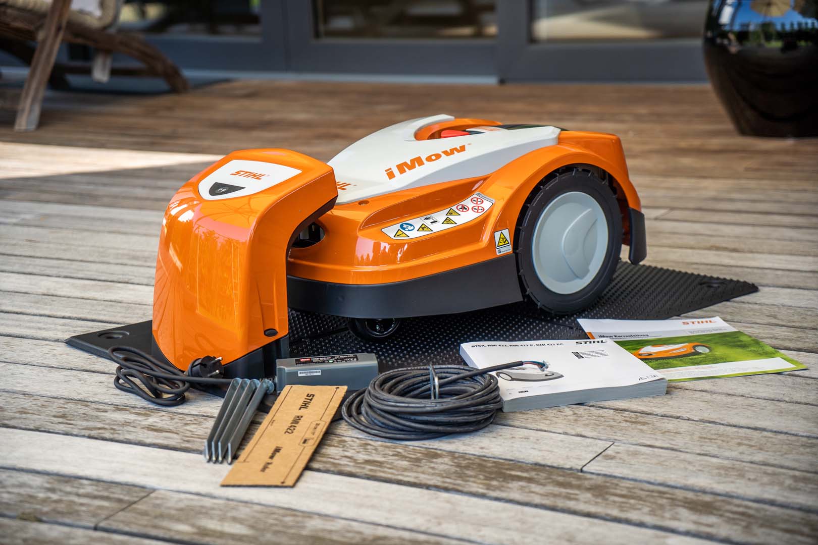 STIHL iMOW® Mähroboter 422 mit Kabel und Bedienungsanleitung vor der Installation auf einer Holzterrasse