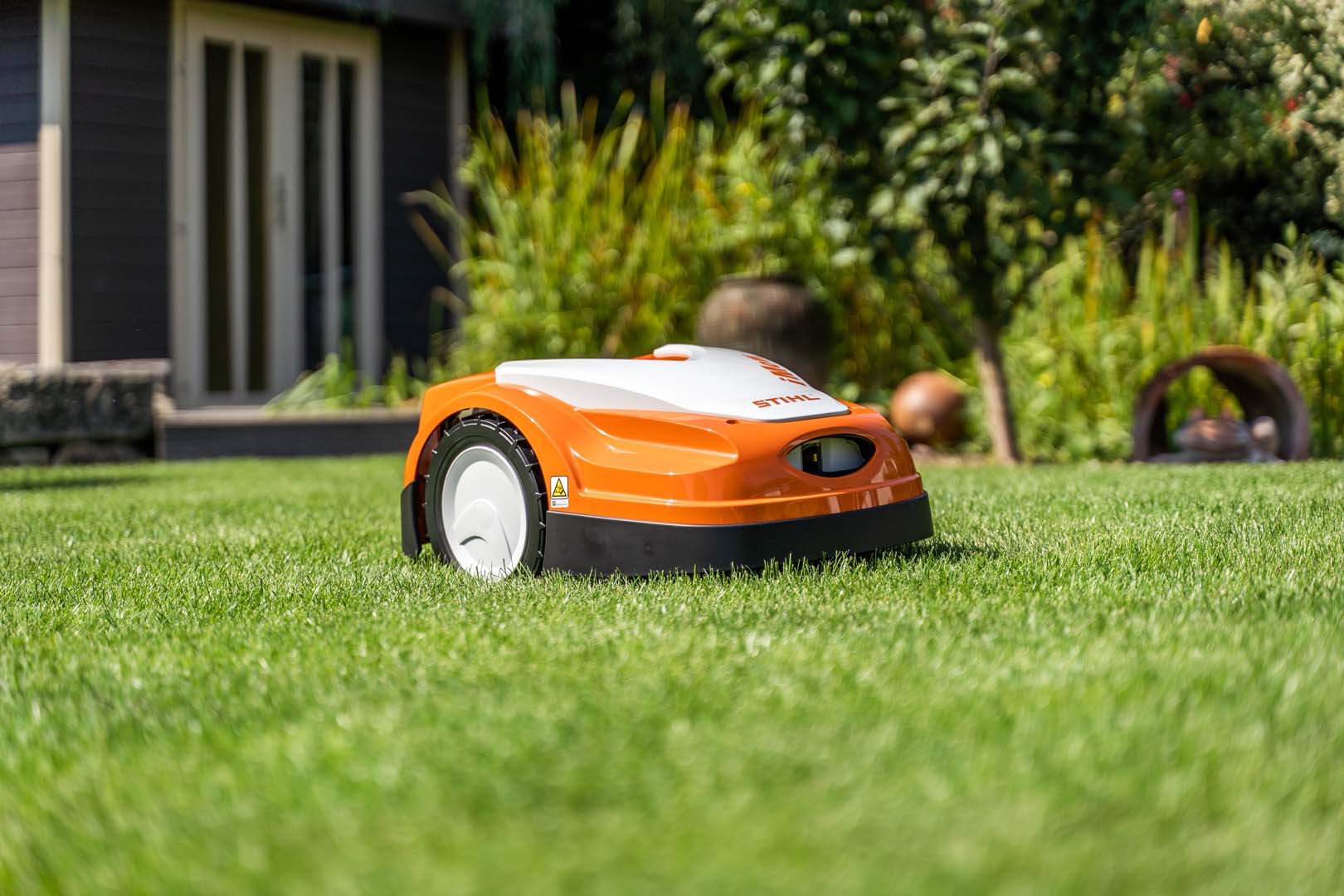 STIHL iMOW® Mähroboter auf grünem Rasen im Garten