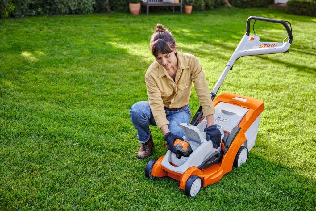 Eine Frau mäht mit einem STIHL Akku-Rasenmäher eine Rasenfläche