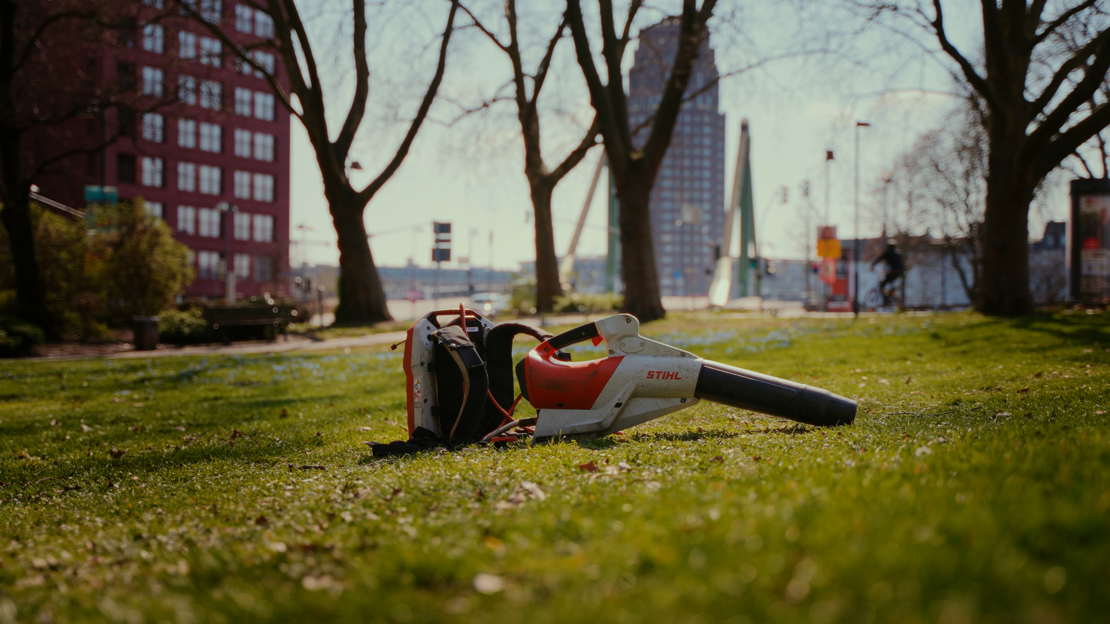 STIHL Akku AP Blasgerät steht mit rückentragbarer Akkuladestation auf einer Wiese in Frankfurt