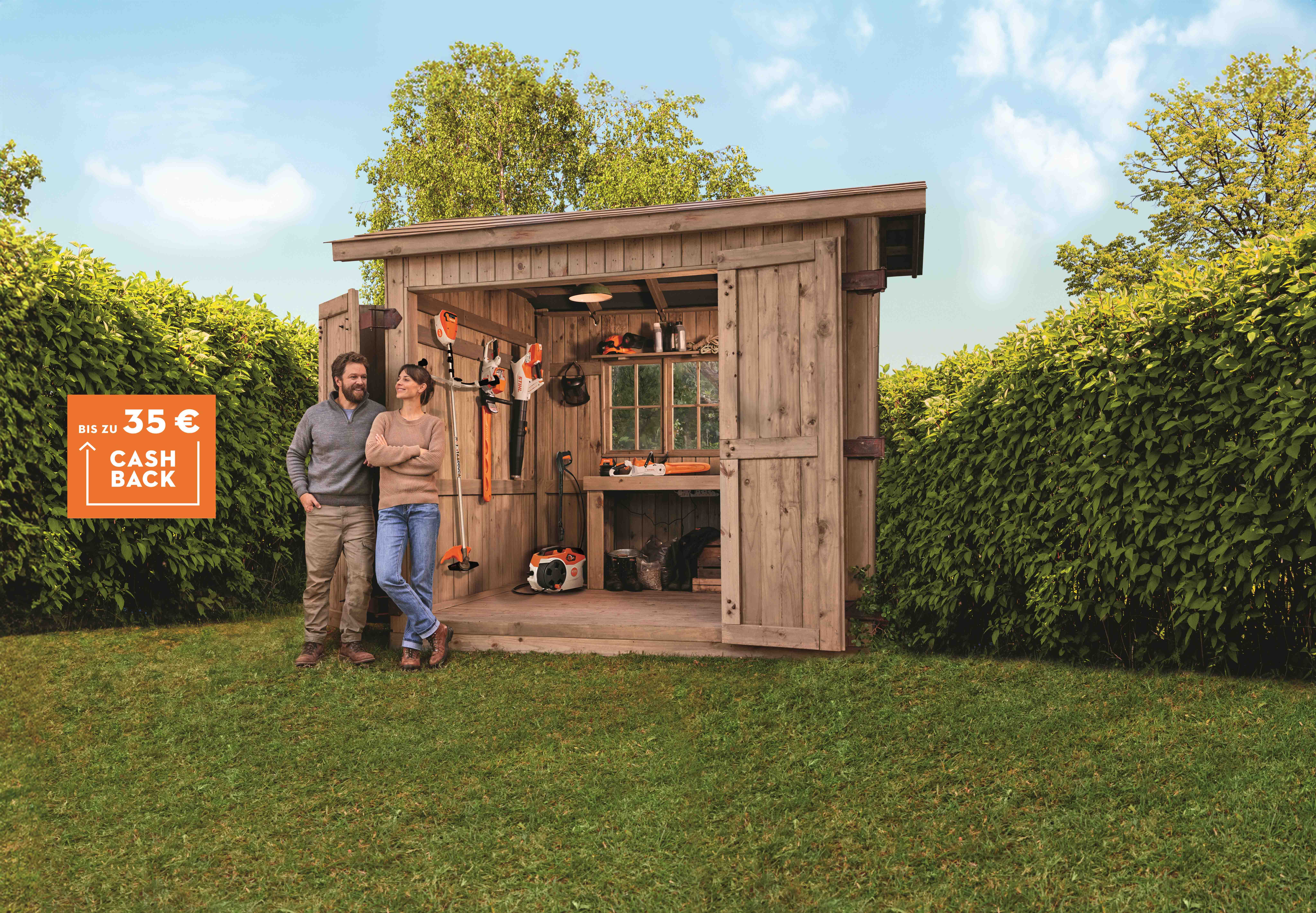 Diverse STIHL Akku Produkte aus dem Akku AK-System mit zwei Personen vor einer Holzhütte.