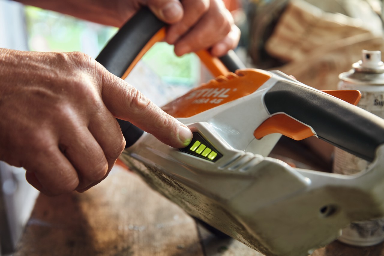 Person überprüft den Ladezustand der Akku-Heckenschere STIHL HSA 45.