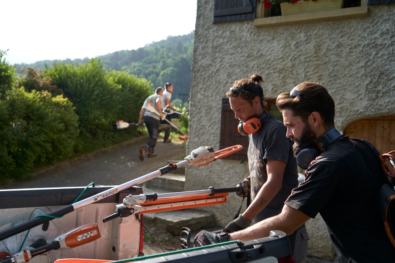 Julien Loquarelli, Landschaftsgärtner, lädt gemeinsam mit Mitarbeitenden die STIHL Geräte aus dem Fahrzeug aus.