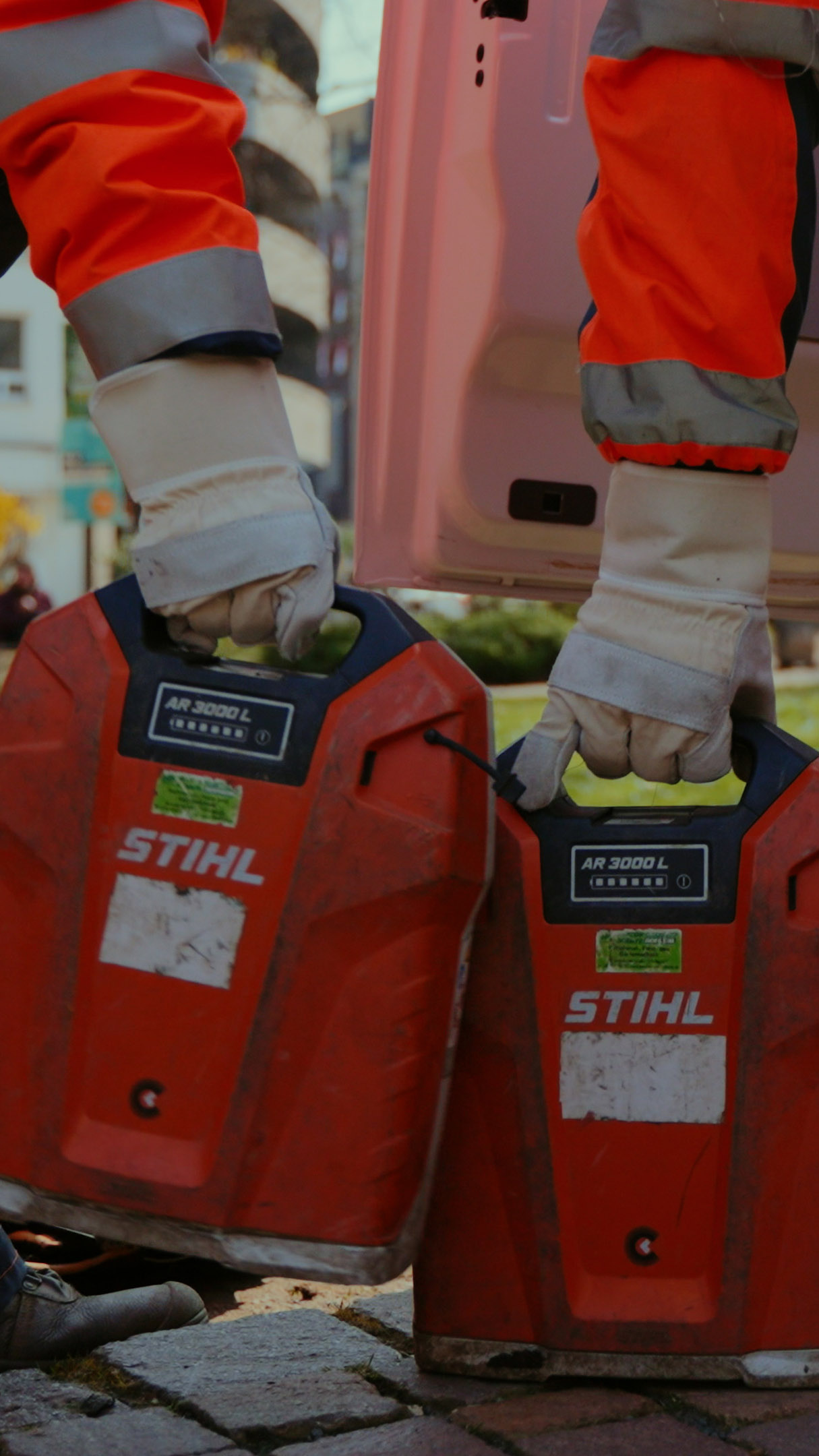 Zwei Profis halten STIHL rückentragbare Akkuladegeräte in der Hand