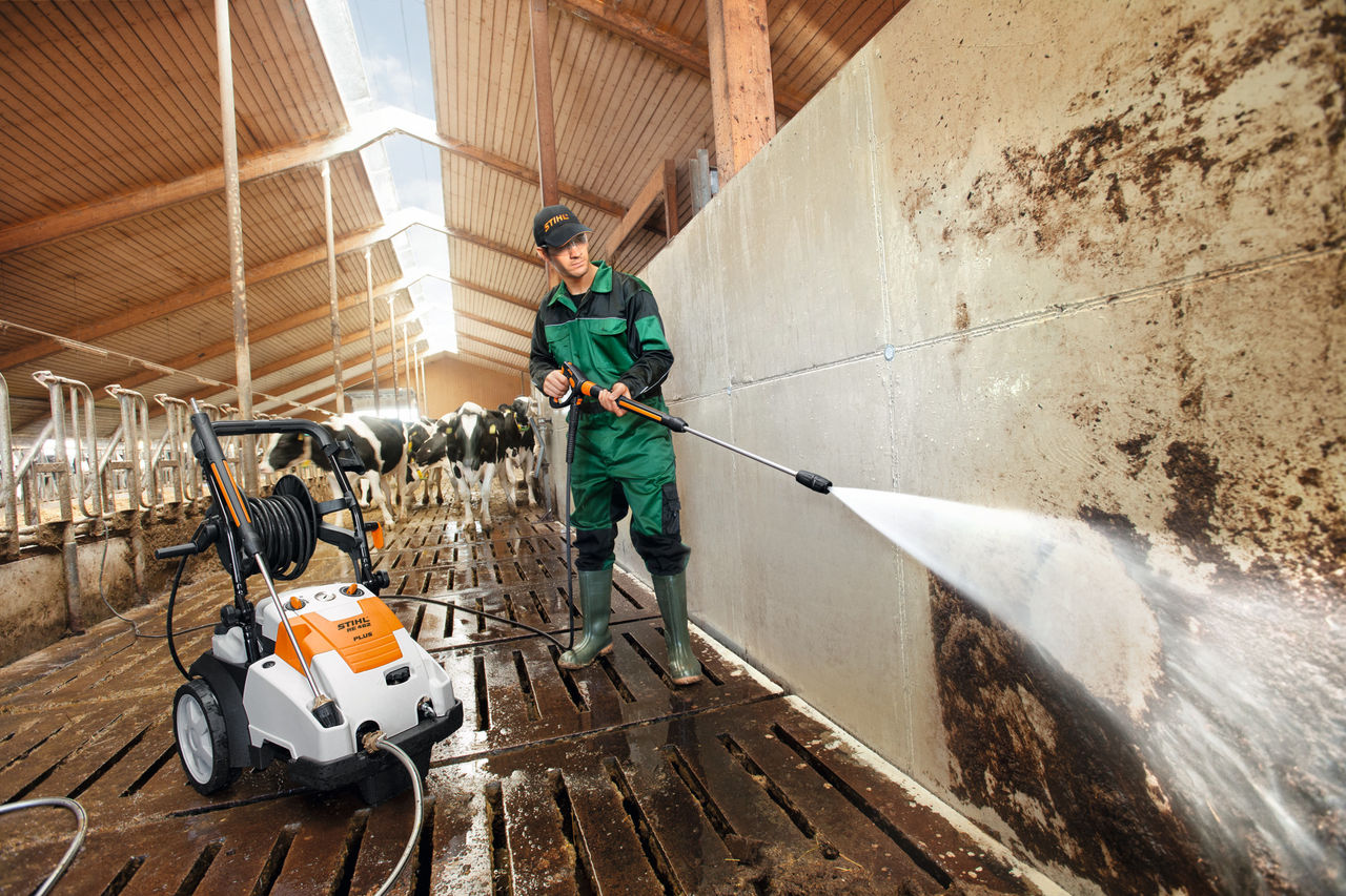 Man reinigt Kuhstall mit einem Hochdruckreiniger STIHL RE 462 PLUS und Flachstrahldüse.
