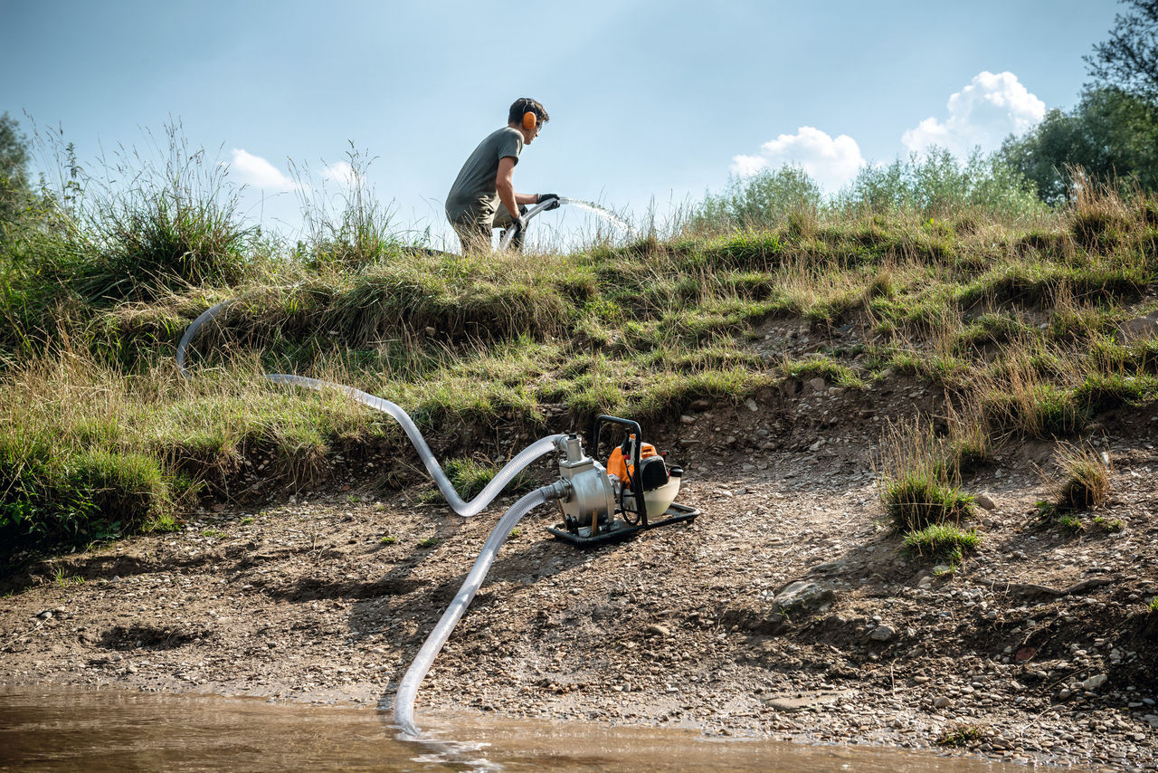Mann pumpt Wasser mit der STIHL Wasserpumpe WP 230 aus einem Wasserbecken.