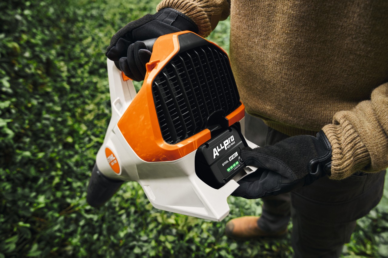 Ein Mann schaltet den Akku seines kabellosen Laubbläsers STIHL BGA 110 mit dem Akku STIHL AP 30.1 Evo 1 ALLPRO ein