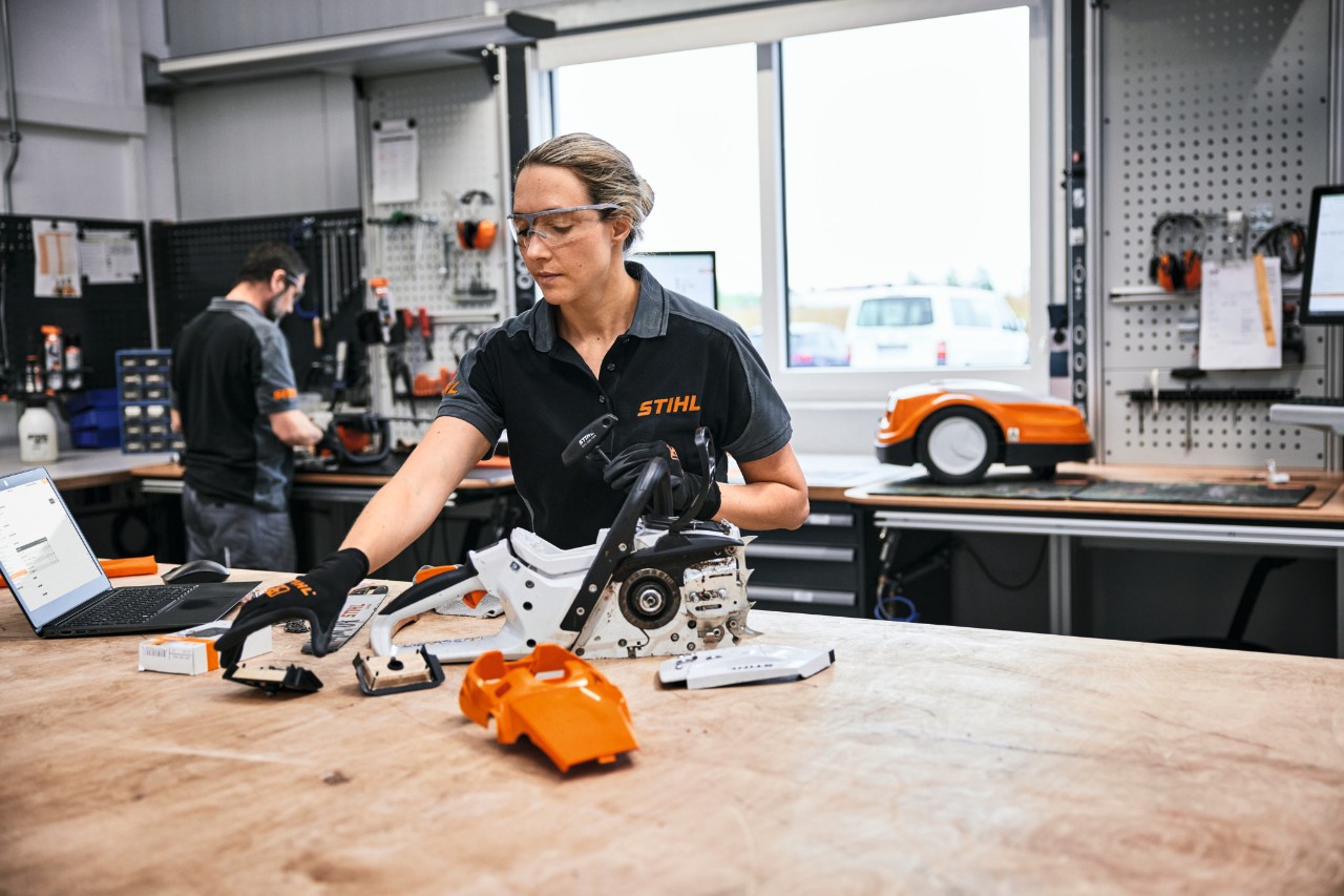 Eine Frau baut in einer Werkstatt eine STIHL Motorsäge nach der Wartung zusammen