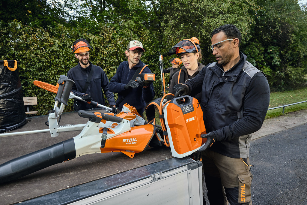  Ein Team von Garten- und Landschaftsbauern holt mit STIHL Profi-Akkugeräten ihre Ausrüstung von der Ladefläche eines Autos
